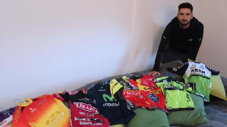 Enrique Sanz, este lunes por la tarde en su casa de Orkoien, con todos los maillots que ha vestido desde juvenil hasta profeisonal en los últimos 16 años