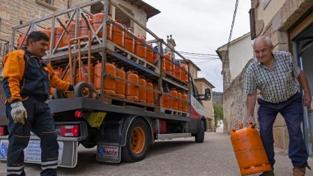 Un repartidor de bombonas tradicionales de Repsol entrega una  a Javier Urabayen Gil, de 78 años, en el pueblo de Luquin (Tierra Estella)
