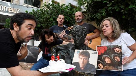 El periodista Adolfo Iglesias, autor del libro 'Juan y John, el profesor y Lennon en Almería para siempre' celebra junto a varios aficionados a los Beatles, el 81 cumpleaños del John Lennon, frente a la estatua del musico inglés en Almería.