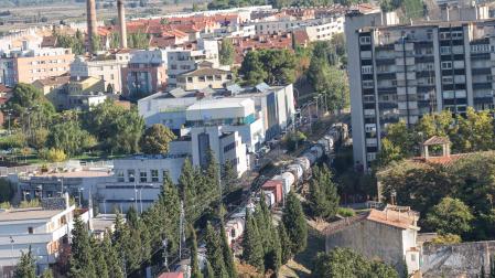Un tren atraviesa el casco urbano de Tudela. A la derecha, el edificio del paseo de Pamplona situado a un lado de la vía