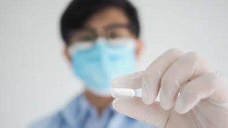 Un sanitario sostiene una pastilla de Molnupiravir