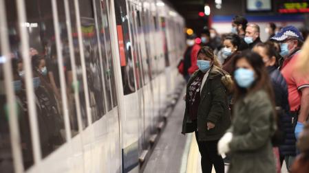 Viajeros con mascarillas en un andén de la estación de metro de Nuevos Ministerios en Madrid