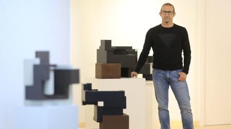El escultor Eduardo Lacoma posa junto a algunas de sus obras instaladas en la exposición Escuchando cubos de la galería Ormolú