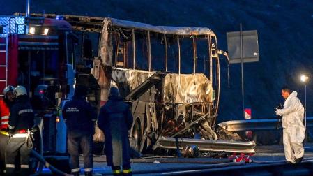 Bomberos y policías inspeccionan los restos del autobús que ha ardido en Bulgaria matando a 45 peronas, 12 de ellos niños