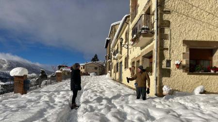 Dos vecinos conversan, ayer, en la carretera de acceso a Petilla de Aragón cubierta por varios cm de nieve