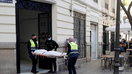 Operarios del retén fúnebre sacan el cadaver de mujer de 30 años de edad que ha sido encontrada este sábado en una vivienda de València asesinada presuntamente a manos de un hombre con el que mantenía una relación sentimental