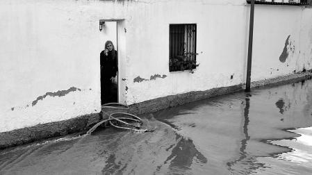 Una mujer habla por teléfono, en la puerta de una vivienda en Funes, localidad que ayer se llevó lo peor de la riada