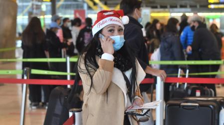 Una mujer con un gorro de Papa Noel en el aeropuerto de Adolfo Suárez, el día previo a la Nochebuena
