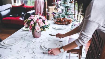 Una mujer prepara la mesa por Navidad