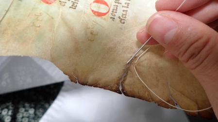 Costura de un desgarro en un documento restaurado