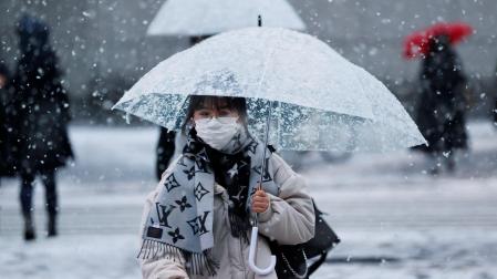 Una mujer con una mascarilla en una calle nevada en Tokio