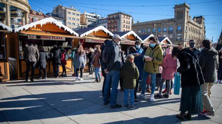 Varias personas disfrutan del último día frente a los puestos de la feria navideña de la Plaza del Castillo