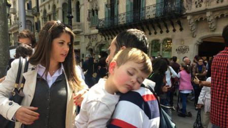 Niño dormido en brazos de un adulto junto a la Casa Batlló, en Barcelona, en 2017