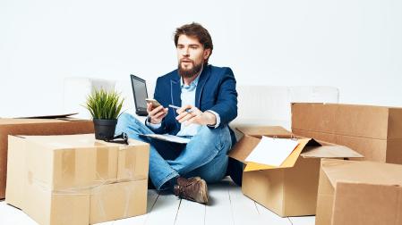 Un hombre realiza gestiones desde su casa a través del teléfono y con el portátil a su lado