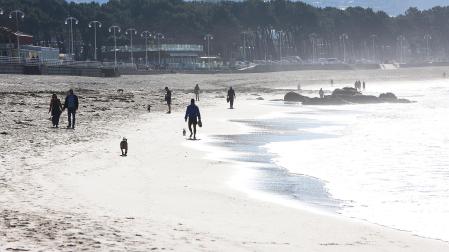 Varias personas caminan este martes en la playa de Samil de Vigo en una jornada soleada
