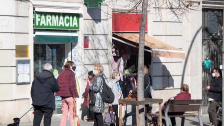 Varias personas guardan cola ante una farmacia del barrio del Guinardó de Barcelona