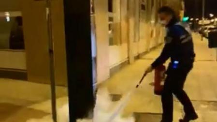 Un agente de la Policía Municipal apaga el incendio de un parquímetro