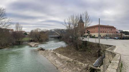 Viandantes por el puente de Santa Engracia, con el azud del mismo nombre en el río y partido por la mitad