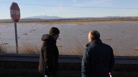 Dos personas miran campos inundados en las inundaciones de diciembre, en la zona de Valtierra