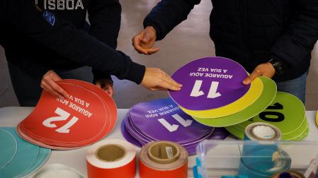 Dos voluntarios preparan carteles informativos en un colegio electoral de Lisboa
