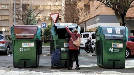 Una mujer deposita una bolsa en un contenedor en Pamplona