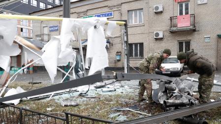 Oficiales de policía inspeccionan los restos de un misil que cayó en una calle de Kiev