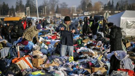 Una persona busca entre la cantidad de ropa donada para los ciudados procedentes de Ucrania que este domingo han cruzado la frontera con Polonia