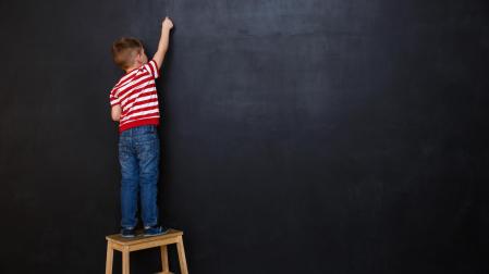 Niño escribiendo con una tiza en una pizarra