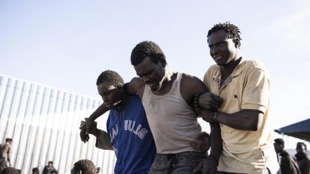 Un migrante es ayudado por sus compañeros, tras conseguir saltar la valla de Melilla