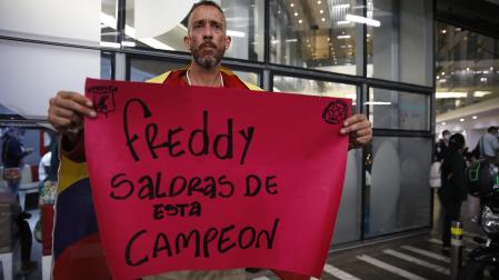 Un aficionado sostiene un cartel de ánimo para el exfutbolista a las puertas de la clínica Imbanaco donde permanece ingresado