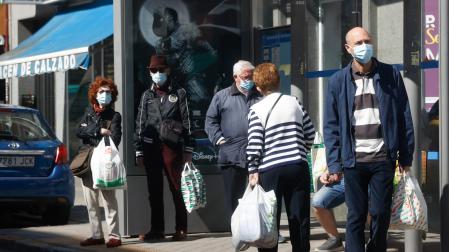 Varias personas con mascarilla esperan al autobús este lunes en Madrid