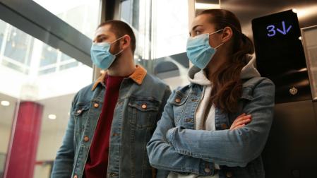 Dos personas con mascarilla en un ascensor