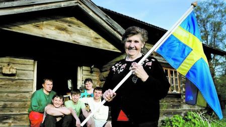 Una familia en Gammalsvenskby (Ucrania), con la bandera de Suecia