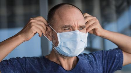 Un hombre, ajustándose una mascarilla