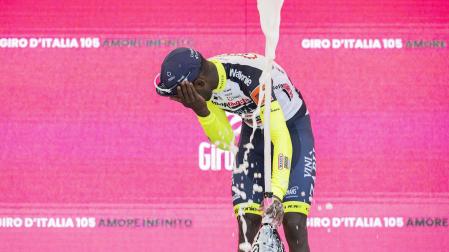 El eritreo Biniam Girmay se duele tras recibir el impacto del corcho del champán en el podio