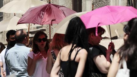 Varias personas se protegen del sol con paraguas en una calle de Valencia