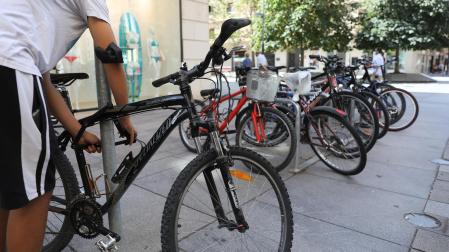 Un ciudadano pone el candado a una bicicleta en Pamplona