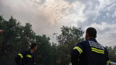 Dos bomberos observan un helicóptero trabajando en el incendio de la Sierra de la Culebra