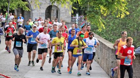 Un grupo de corredores en la San Fermín Media Maratón de 2019 cruzando el Portal Nuevo, una zona por la que volverán a pasar mañana los recorridos de La Media San Fermín