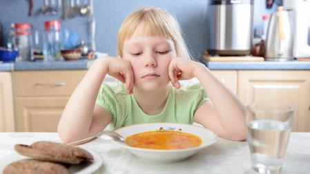 Una niña, frente a un plato de comida