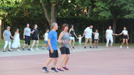 Dos monitores, en el centro de un círculo que formaron los participantes, les muestran uno de los pasos de los bailes festivos.