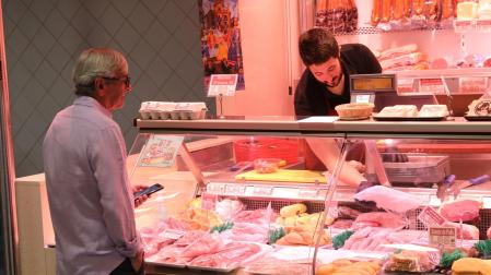 Un carnicero atiende a un cliente en la zona del mostrador del establecimiento donde se expone la carne de pollo