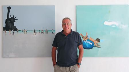 ñaki Pardos posa junto a dos obras de la exposición Mix celánea, unas pinturas en las que el artista recurre a la playa y los bañistas como tema principal.