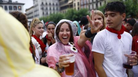 Dos jóvenes, bebida en mano, en la plaza del Castillo tras el Chupinazo