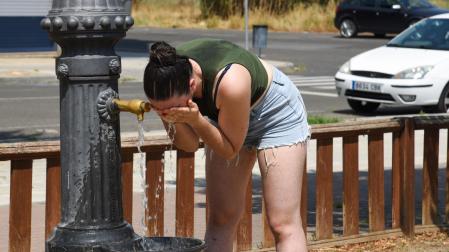 Una joven se refresca en una fuente