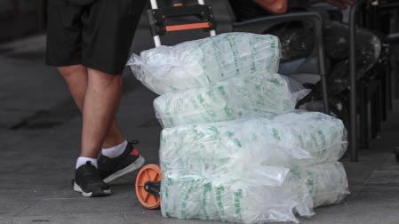 Un repartidor con varias bolsas de cubitos de hielo