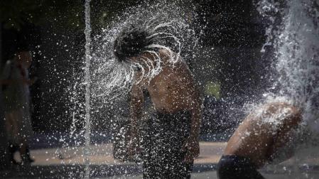 Dos jóvenes, refrescándose recientemente en la fuente de chorros de la Plaza de Yamaguchi en Pamplona