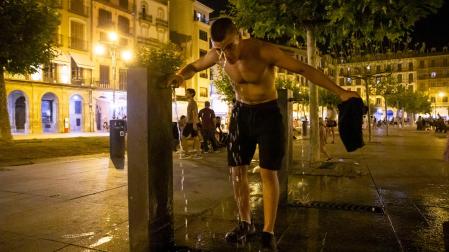 Un joven aprovecha el agua de una de las fuentes de la Plaza del Castillo para refrescarse