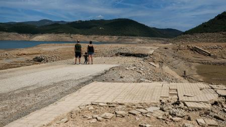 Una familia observa el nivel bajo del embalse de Rialb, en Lleina, que ha dejado al descubierto restos del antiguo pueblo de Tiurana