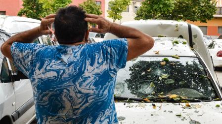 Un hombre con las manos en la cabeza al ver el estado de la luna de su vehículo, como consecuencia de la tormenta de granizo en la Bisbal d’Empordà, Girona